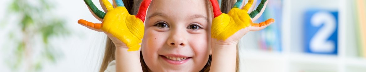 a child smiling with colors on hand