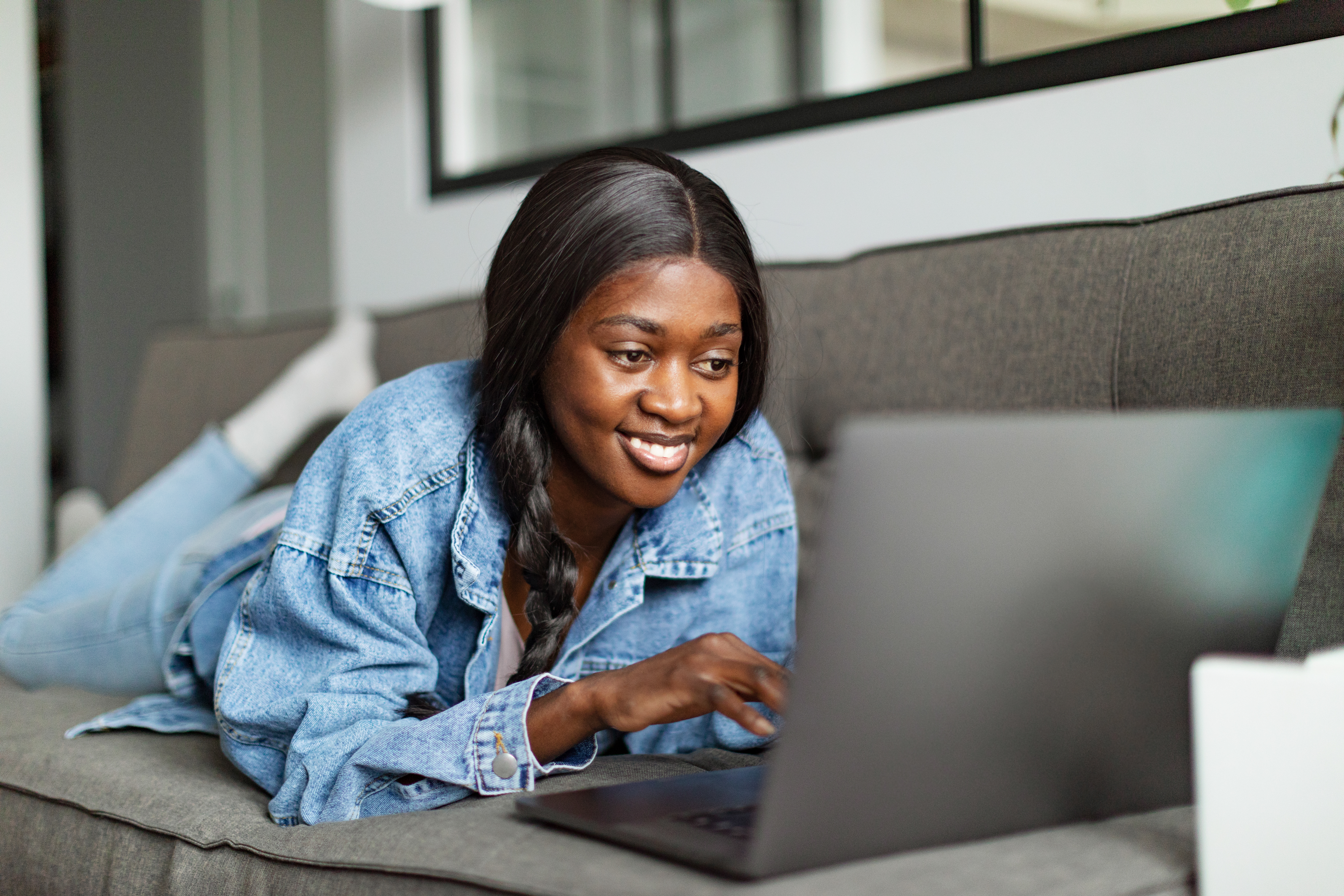 Girl laying down with her laptop looking at Catholic Charities